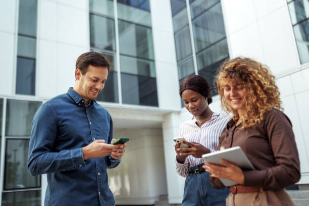 istock Three young colleagues using smart phone and digital tablet outdoors 2158492556
