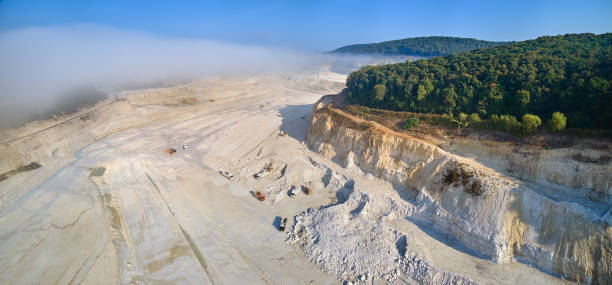 Aerial view of open pit mining of limestone materials for construction industry with excavators and dump trucks.