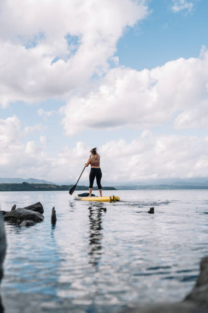 istock A woman is standing on a surfboard in the ocean 2158500941