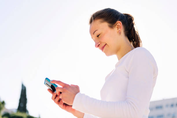 smiling young woman using mobile phone, concept of technology of communication and social media