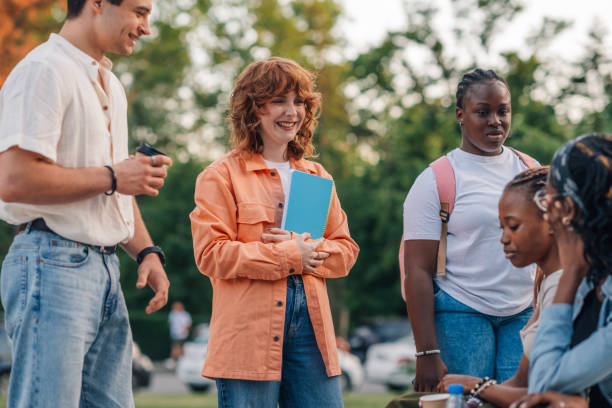 istock Happy college girl with textbook smiling at diverse classmates at campus 2158502437