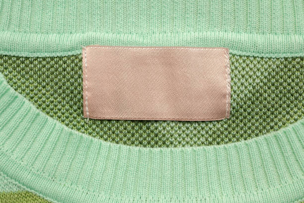 Brown blank laundry care clothes label on green shirt fabric background