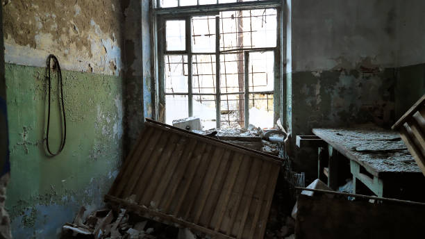 istock An abandoned, dilapidated room with peeling paint, broken windows, and debris scattered on the floor 2158502922