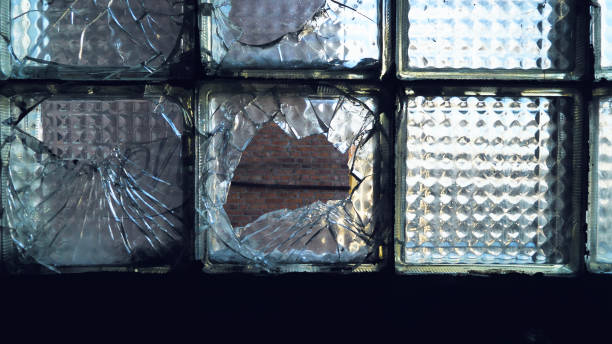istock Close-up of a broken glass block window with several panes shattered, exposing the brick wall behind 2158502941