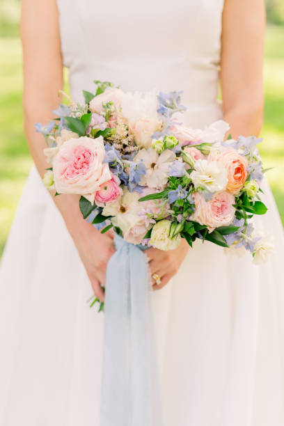 istock A bride is holding a summer pink summer bouquet with blue ribbon. 2158503308