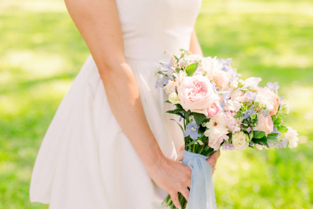 istock A bride is holding a beautiful pink bouquet and light blue ribbon. 2158503403