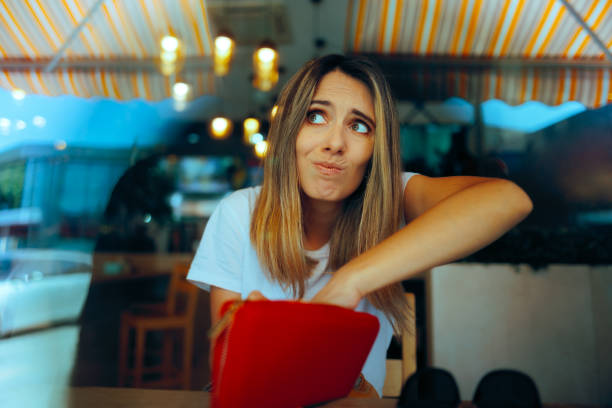 istock Woman in a Restaurant Checking her Wallet for Tip Cash 2158507479