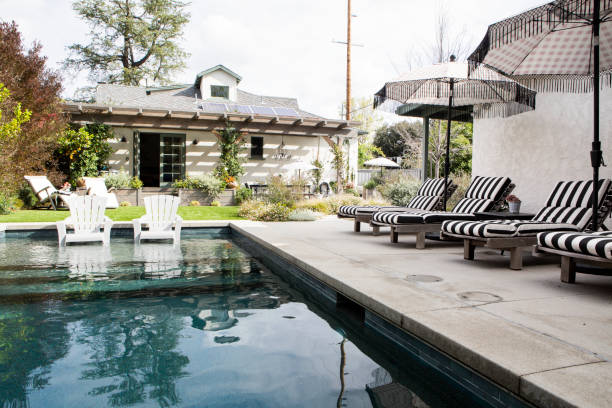 istock Wooden seats by a pool with parasols 2158510640