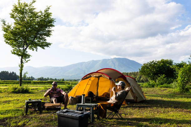 A male and female relax at their camp site enjoying a drink with Mt. Iwate in the background.