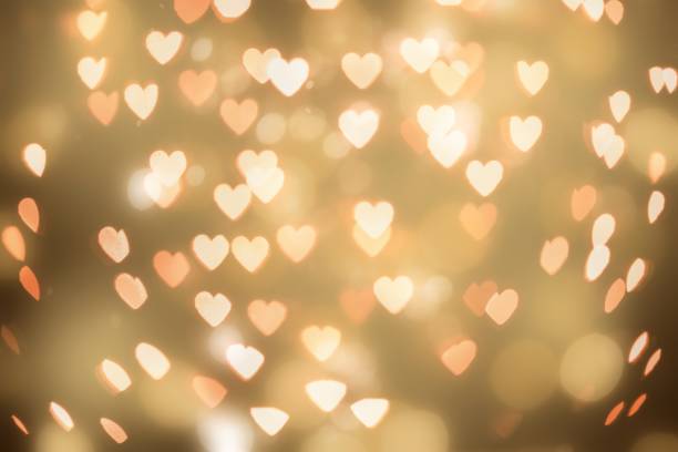 istock Gold glitter heart bokeh sequin confetti on black background 2158515296