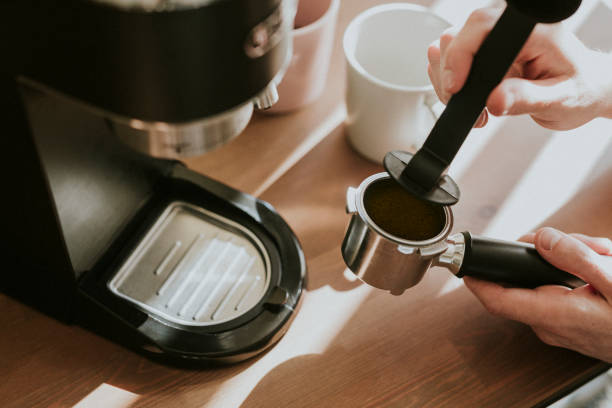 istock Barista pressing ground coffee in a coffee machine filter 2158517411