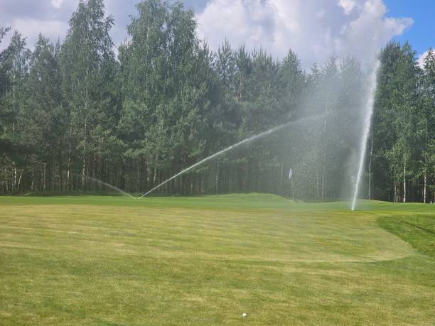 istock sprinkler system watering the green grass on a golf course in the summer 2158520162