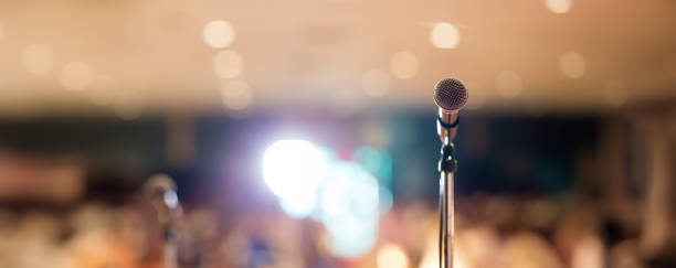 Microphone in concert hall or conference room soft and blur style for background. Microphone over the Abstract blurred photo of conference hall or seminar room background.