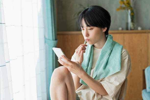 istock Woman looking at her mobile phone while brushing her teeth. 2158521974