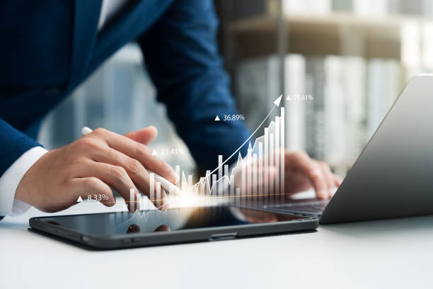 istock Businessman use laptop and tablet digital chart graphing company growth plan and up arrow. 2158524704