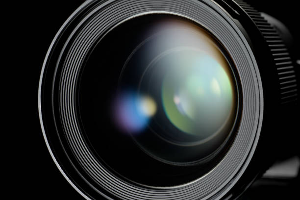 Photo or video camera lens with light reflections close-up on the black background.