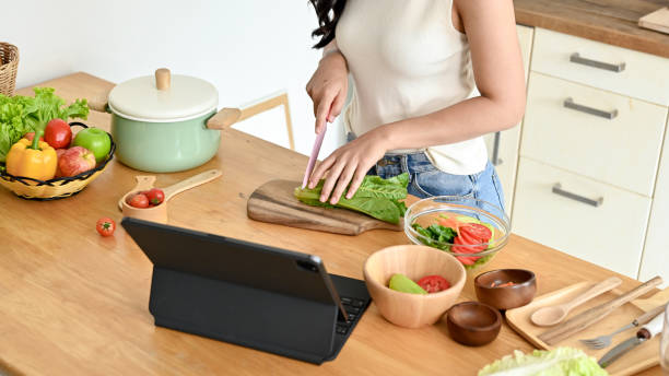 istock Beautiful woman searching recipe on tablet while cooking in kitchen 2158533323