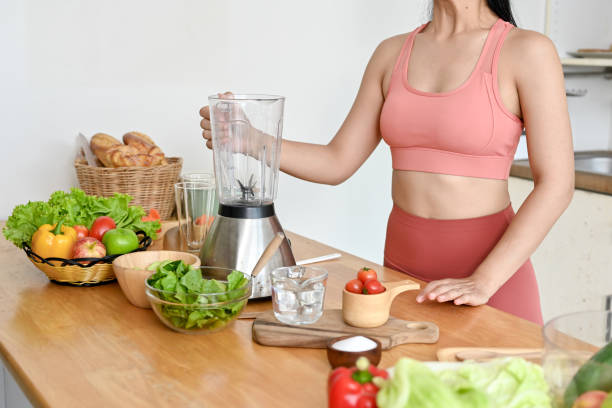 istock young woman making smoothie with fresh vegetables in kitchen. 2158533471