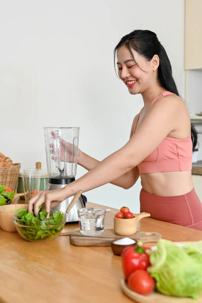 istock young woman making smoothie with fresh vegetables in kitchen. 2158533474