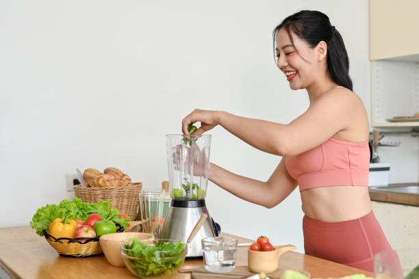istock young woman making smoothie with fresh vegetables in kitchen. 2158533477
