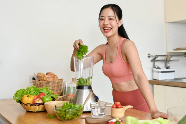 istock young woman making smoothie with fresh vegetables in kitchen. 2158533495