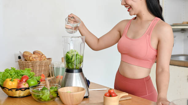 istock young woman making smoothie with fresh vegetables in kitchen. 2158533508