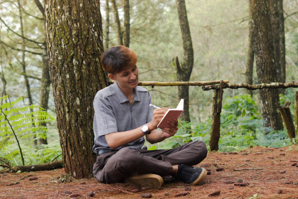 istock Portrait of confident Asian man writing on notebook while thinking and looking away in the nature forest. Peaceful and relaxing healthcare wellness 2158533531