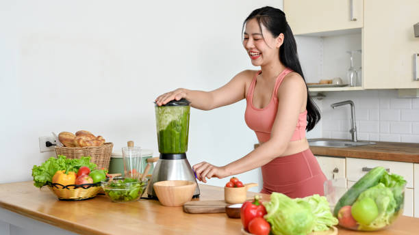 istock young woman making smoothie with fresh vegetables in kitchen. 2158533550