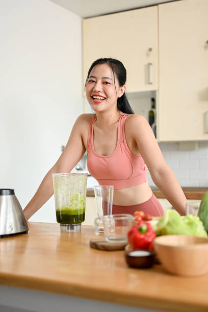 istock young woman making smoothie with fresh vegetables in kitchen. 2158533551