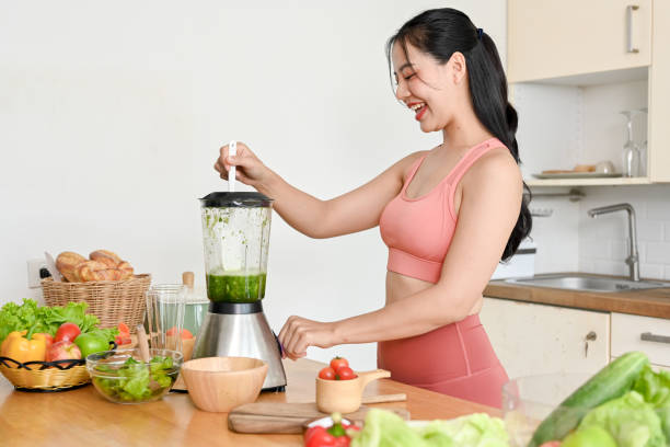 istock young woman making smoothie with fresh vegetables in kitchen. 2158533552