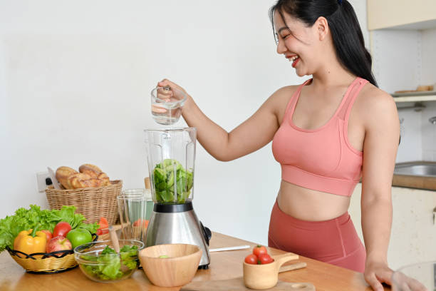istock young woman making smoothie with fresh vegetables in kitchen. 2158533553