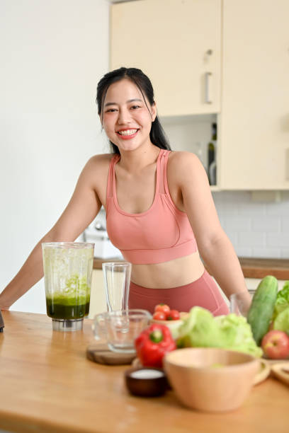 istock young woman making smoothie with fresh vegetables in kitchen. 2158533561