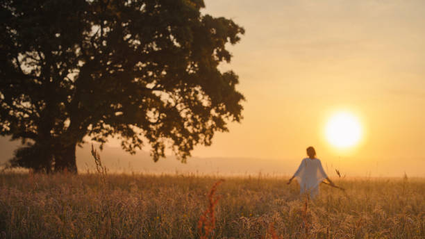 istock Serene Woman Strolls in Sunset-Lit Meadow 2158534498