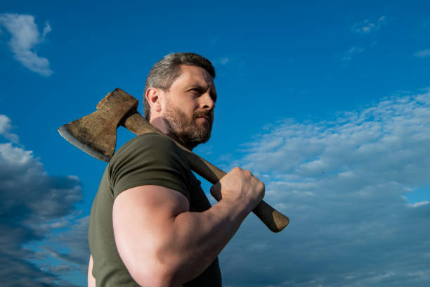 brutally man with axe. lumberjack man hold ax. brutal man on sky background.