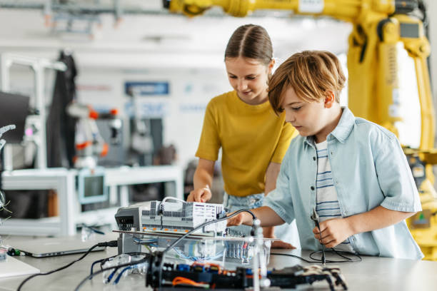 istock Two classmates working togeter on circuit board, building robot in after-school robotics club. Children learning robotics in Elementary school. 2158536859