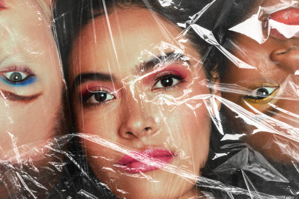 A young woman with her head wrapped in plastic while isolated on a black background