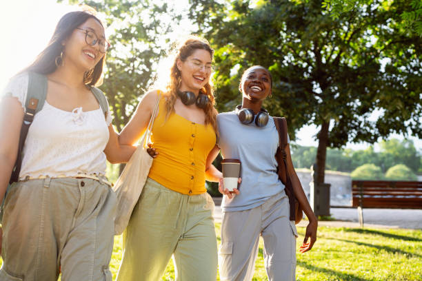 Modern multiracial female University students walking through the campus park
