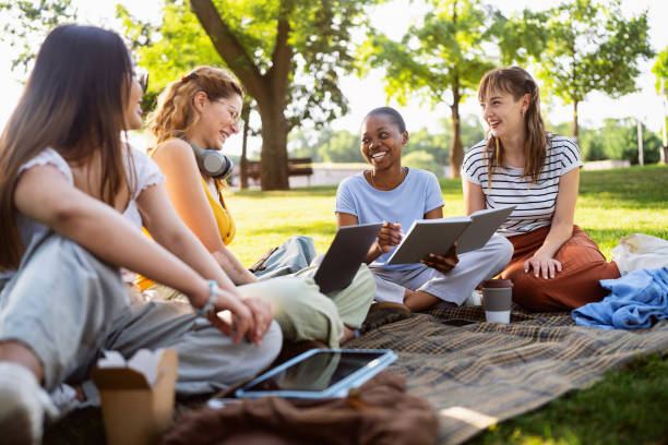 Modern multiracial female University students studying together at the campus park