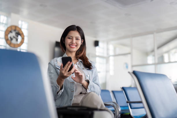 istock Smiling Tourist Using Smartphone While Waiting in Modern Airport Terminal 2158542253