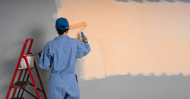 istock Female worker painter paints a wall, back view. Professional builder makes repairs in new house. 2158544714