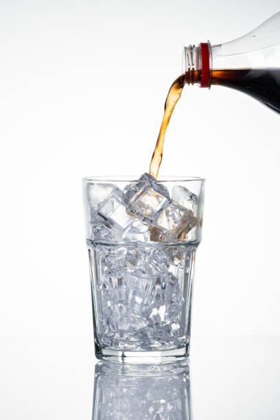 istock Cold carbonated drink being poured over ice cubes into a glass 2158544797