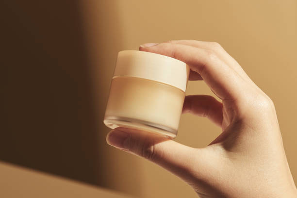 istock Hand holding beige cream pot 2158547130