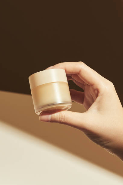 istock Hand holding beige cream pot 2158547131