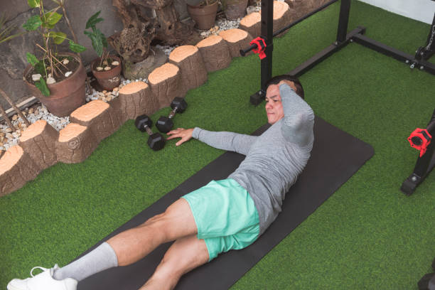 istock A fit asian guy does oblique crunches while lying on a black mat. Leg raised for added challenge. Working out his midsection and core at his home gym. 2158547400