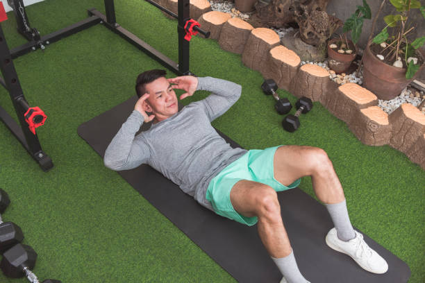 istock A middle-aged man does abdominal crunches while lying on the floor. Working out his core at his home gym. 2158547503