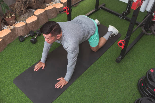 istock A fit asian man in a gray sweater performs a cat stretch on a black mat. Warming up before a workout at his home gym. 2158547587
