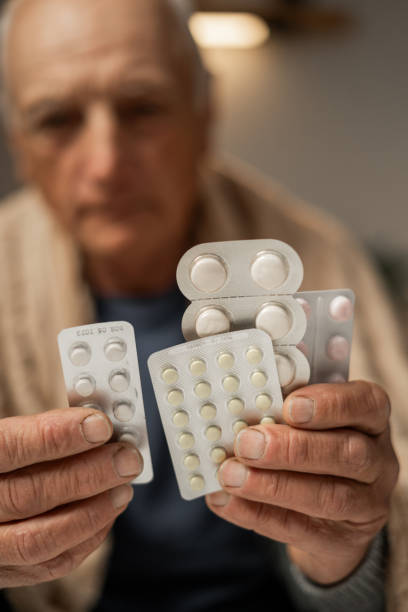 istock sick man suffering from virus is at home, looking at medication 2158553971