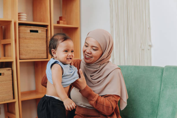 istock Asian Muslim mother changing her baby's clothes. 2158554444