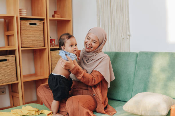 istock Asian Muslim mother changing her baby's clothes. 2158554448