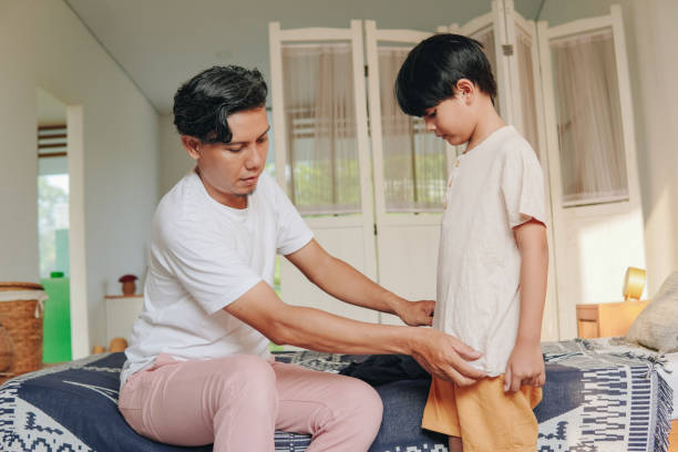 istock Young Asian father changing his son's clothes. 2158554497